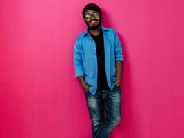 indio sonriente joven hombre con azul camisa y lentes posando en rosado antecedentes foto