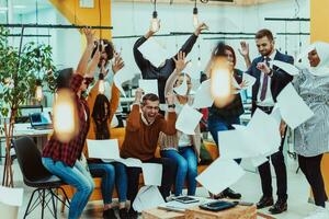 Group of business people throwing paper in air at modern startup office, team success and job done concept photo