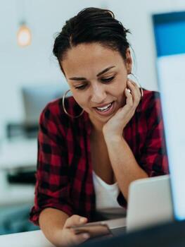 Woman sitting at workplace desk holds smartphone staring at laptop, synchronize data between computer and gadget in office, using corporate devices and business application, plan work, using organizer photo