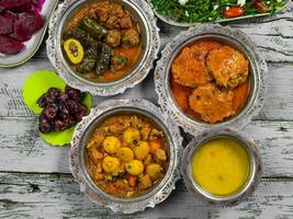 eid Mubarak tradicional Ramadán iftar cena. clasificado sabroso comida en auténtico rústico platos en de madera azul antecedentes. turco bosnio comida carne brocheta, Agave, sarma, klepe, sogan dolma. foto