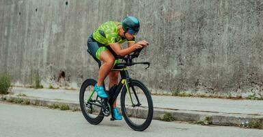 Full length portrait of an active triathlete in sportswear and with a protective helmet riding a bicycle. Selective focus photo