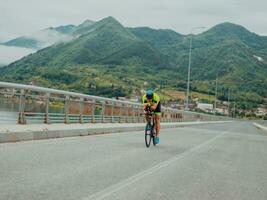 Full length portrait of an active triathlete in sportswear and with a protective helmet riding a bicycle. Selective focus photo