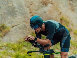 lleno longitud retrato de un activo triatleta en ropa de deporte y con un protector casco montando un bicicleta. selectivo atención foto