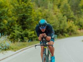 Full length portrait of an active triathlete in sportswear and with a protective helmet riding a bicycle. Selective focus photo