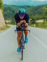 lleno longitud retrato de un activo triatleta en ropa de deporte y con un protector casco montando un bicicleta. selectivo atención foto