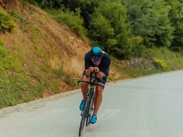 Full length portrait of an active triathlete in sportswear and with a protective helmet riding a bicycle. Selective focus photo