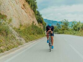 Full length portrait of an active triathlete in sportswear and with a protective helmet riding a bicycle. Selective focus photo