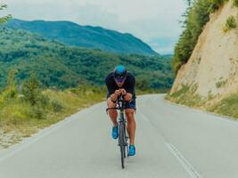 Full length portrait of an active triathlete in sportswear and with a protective helmet riding a bicycle. Selective focus photo