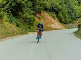 Full length portrait of an active triathlete in sportswear and with a protective helmet riding a bicycle. Selective focus photo