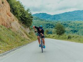 Full length portrait of an active triathlete in sportswear and with a protective helmet riding a bicycle. Selective focus photo