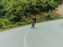 Full length portrait of an active triathlete in sportswear and with a protective helmet riding a bicycle. Selective focus photo