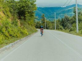 Full length portrait of an active triathlete in sportswear and with a protective helmet riding a bicycle. Selective focus photo