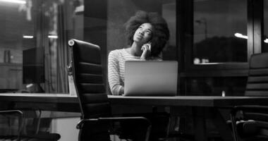 black businesswoman using a laptop in night startup office photo