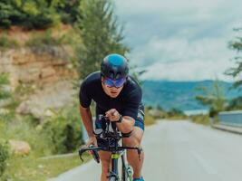 Full length portrait of an active triathlete in sportswear and with a protective helmet riding a bicycle. Selective focus photo