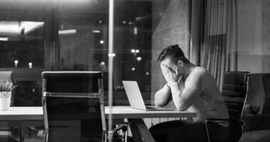 man working on laptop in dark office photo