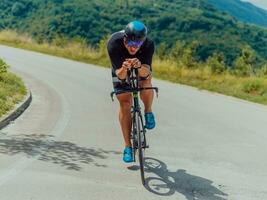 Full length portrait of an active triathlete in sportswear and with a protective helmet riding a bicycle. Selective focus photo