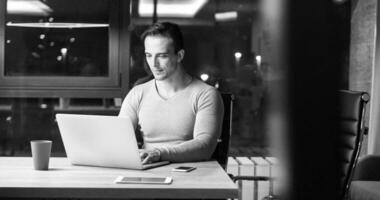 man working on laptop in dark office photo