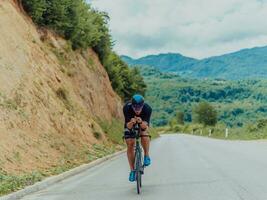 Full length portrait of an active triathlete in sportswear and with a protective helmet riding a bicycle. Selective focus photo