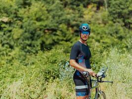 Full length portrait of an active triathlete in sportswear and with a protective helmet riding a bicycle. Selective focus photo