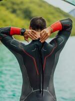 atleta poniendo en un nadando traje y preparando para triatlón nadando y formación en el río rodeado por natural verdor foto