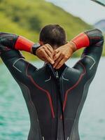 atleta poniendo en un nadando traje y preparando para triatlón nadando y formación en el río rodeado por natural verdor foto