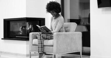 black woman at home reading book photo