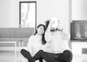 multiethnic couple using tablet computer in front of fireplace photo