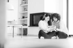 multiethnic couple using tablet computer in front of fireplace photo
