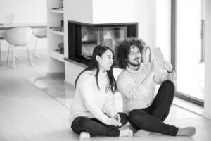 multiethnic couple using tablet computer in front of fireplace photo