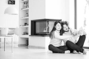 multiethnic couple using tablet computer in front of fireplace photo