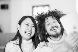 multiethnic couple using tablet computer in front of fireplace photo