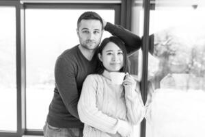 pareja multiétnica disfrutando del café matutino junto a la ventana foto