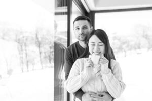 pareja multiétnica disfrutando del café matutino junto a la ventana foto