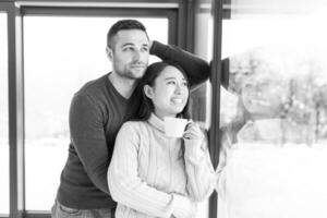 pareja multiétnica disfrutando del café matutino junto a la ventana foto