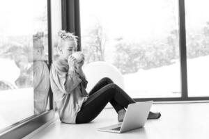 woman drinking coffee and using laptop at home photo