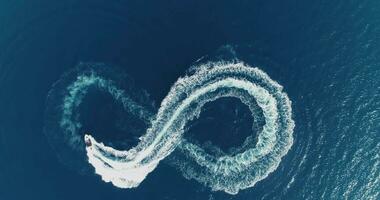 Aerial top view of a white pleasure boat on a summer day. Powerboat turn loop eight on the sea making infinity future concept. photo