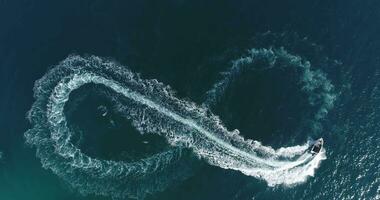 Aerial top view of a white pleasure boat on a summer day. Powerboat turn loop eight on the sea making infinity future concept. photo