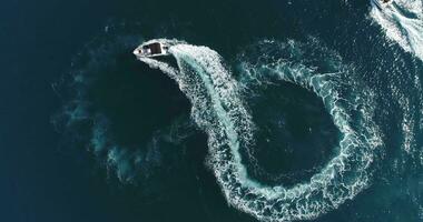 aéreo parte superior ver de un blanco Placer barco en un verano día. lancha fuera borda giro lazo ocho en el mar haciendo infinito futuro concepto. foto