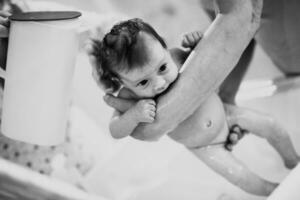 Newborn baby girl taking a  bath photo