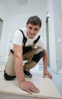 Worker Installing New Laminated Wooden Floor photo