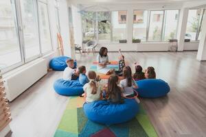 Reading time in an elementary school or kindergarten, a teacher reads a book to children in an elementary school or kindergarten. The concept of pre-school education. Selective focus photo