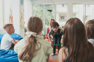 A happy female teacher sitting and playing hand games with a group of little schoolchildren photo