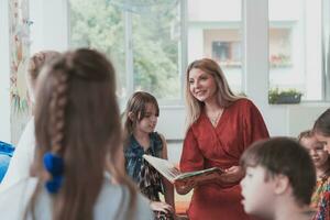 Reading time in an elementary school or kindergarten, a teacher reads a book to children in an elementary school or kindergarten. The concept of pre-school education. Selective focus photo