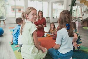 Reading time in an elementary school or kindergarten, a teacher reads a book to children in an elementary school or kindergarten. The concept of pre-school education. Selective focus photo