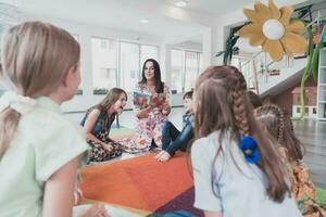 Reading time in an elementary school or kindergarten, a teacher reads a book to children in an elementary school or kindergarten. The concept of pre-school education. Selective focus photo