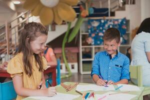 Cute girl and boy sit and draw together in preschool institution photo