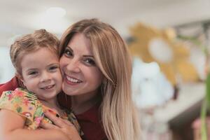 A cute little girl kisses and hugs her mother in preschool photo