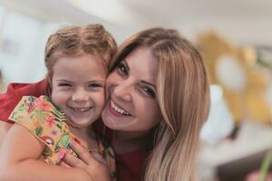 A cute little girl kisses and hugs her mother in preschool photo