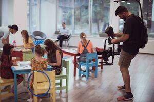 un camarógrafo con un profesional cámara registros para niños socializando en un preescolar institución foto