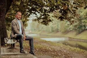 Modern senior businessman sitting on a park bench photo